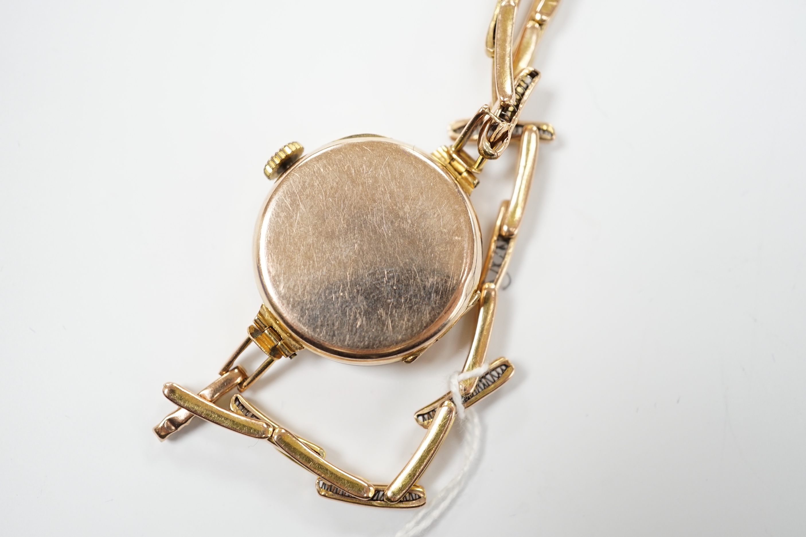 An early 20th century 9ct gold manual wind wrist watch, on a 9ct expanding bracelet, case diameter 25mm, gross weight 14.9 grams.